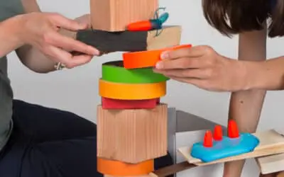 closeup of hands placing a block on a block-disc structure