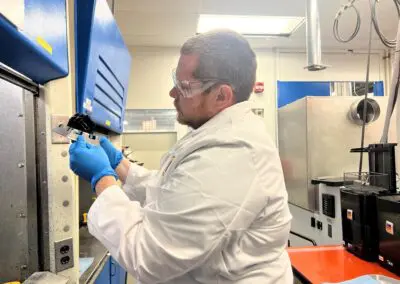 Ben wears a white coat in a lab and works on calibrating a machine.