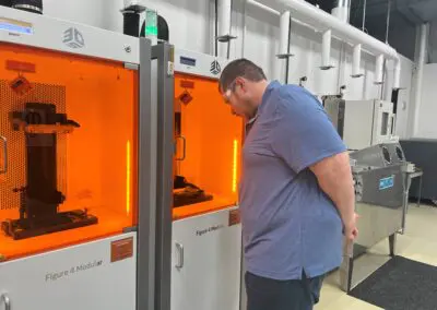 Ben stands in front of a 3d printer looking at the print.
