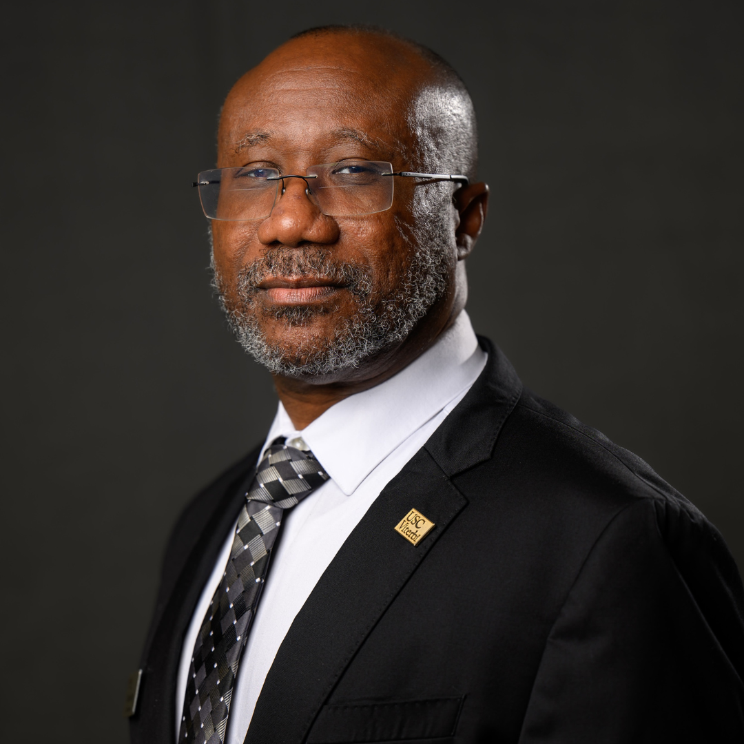 A headshot photo of Darin Gray, DIscoverE Board Member. He is wearing a black suit jacket with white shirt and tie, and a lapel pin that reads USC Viterbi.