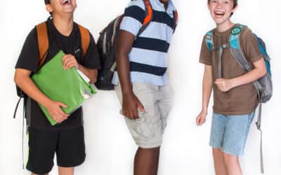3 Middle School boys smiling at the camera with backpacks on