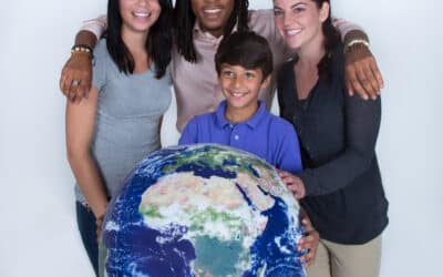 three volunteer engineers stand with a young boy holding a globe