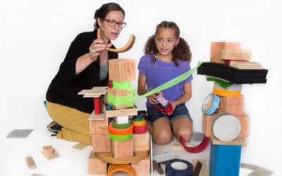 engineer and young girl build a tower out of assorted material for discoverE activity