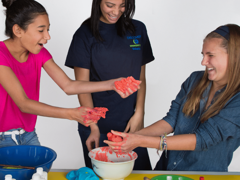 Two girls and their leader make slime. 